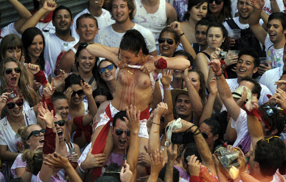A reveller lifts up her top before the start of the San Fermin Festival in Pamplona